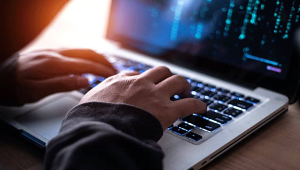 A close up of hands typing on a laptop.