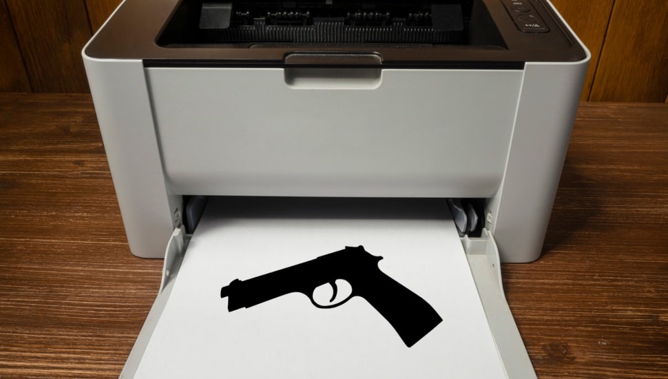 Photo of a gun on a piece of paper coming out of a printer to represent a ghost gun.