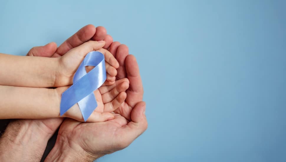 A child holds a blue ribbon symbolizing National Child Abuse Prevention Month, cradled in her father's hands.
