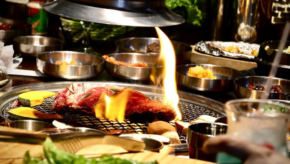 Meat and dishes on Korean BBQ table.