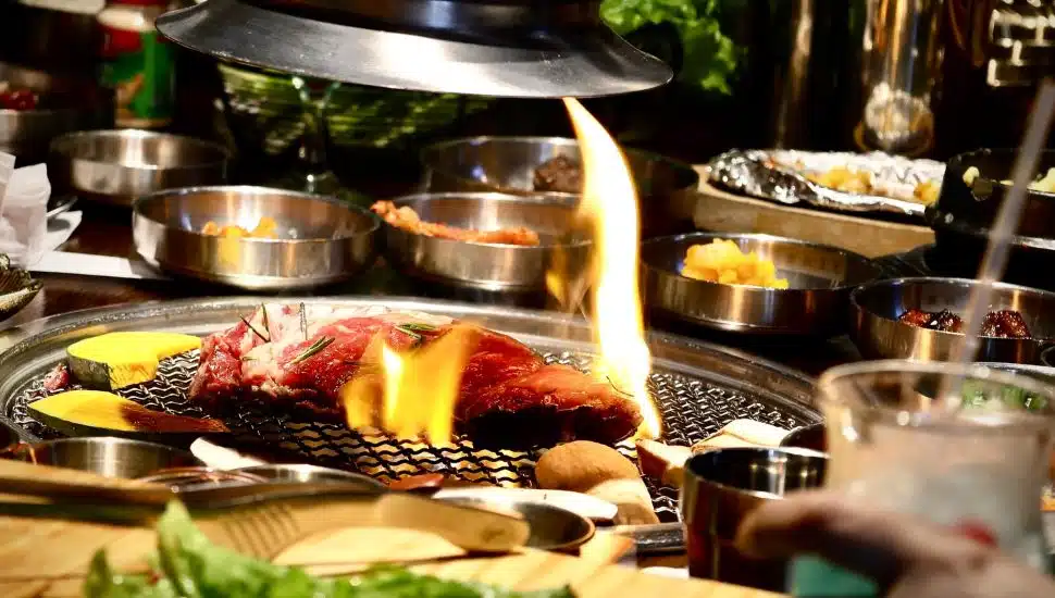 Meat and dishes on Korean BBQ table.