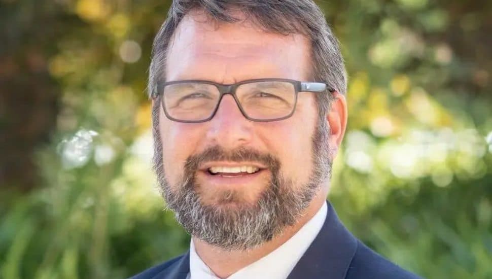 Anthony Rybarczyk headshot wearing suit and glasses.
