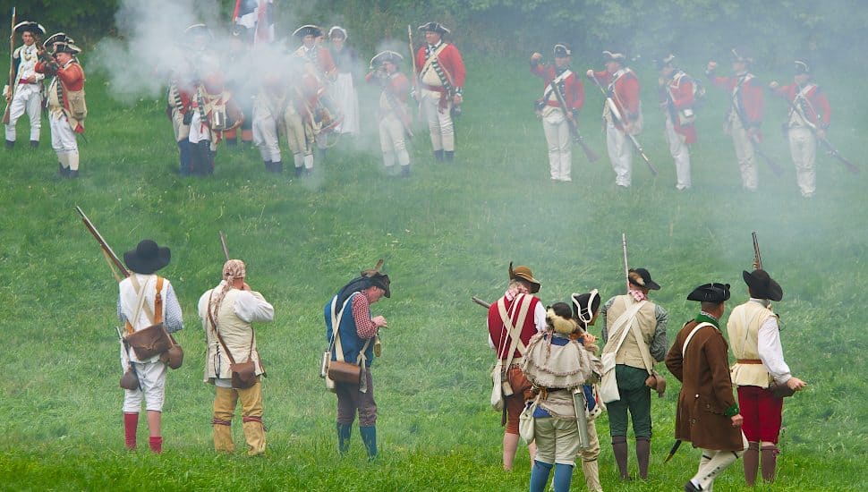 Revolutionary War-era reenactment on a field.