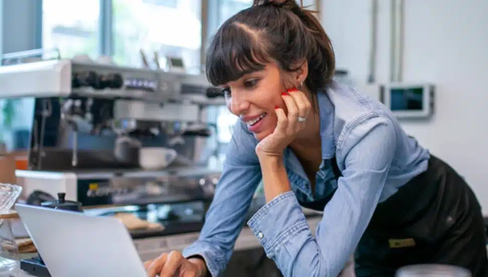 Woman small business owner looks at finances on her laptop.