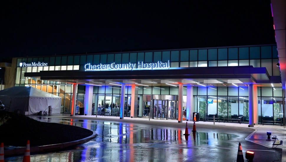 Exterior of Chester County Hospital entrance at night with blue and red lights lit up.