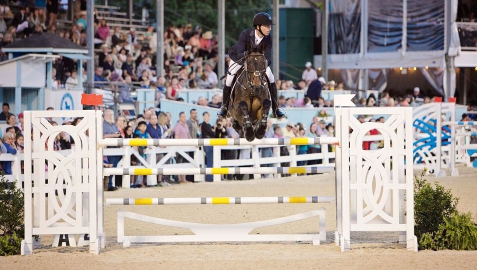 Equestrian jumps over hurdle at horse show.