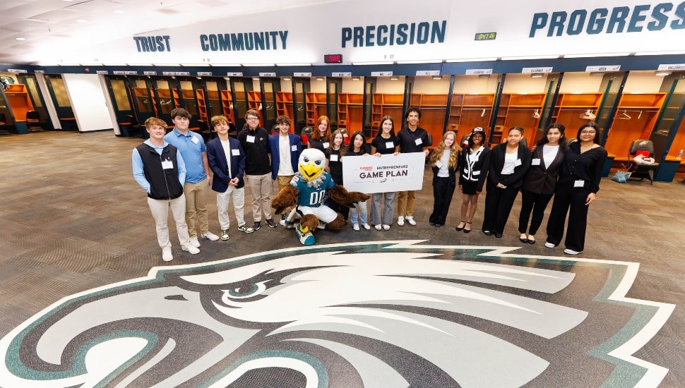 High school students pose for group photo in the Eagles' locker room.