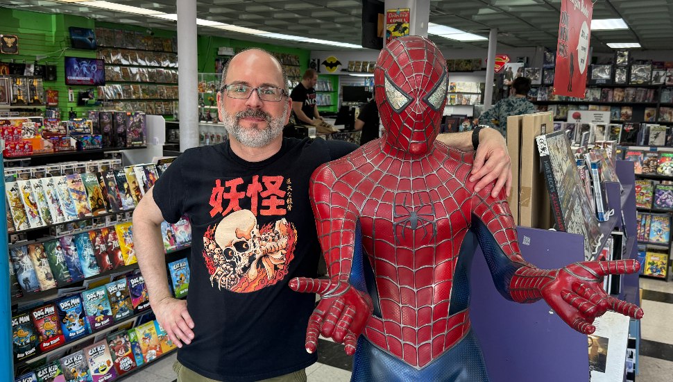 Eric Loyak in store with his arm around Spider Man figure.