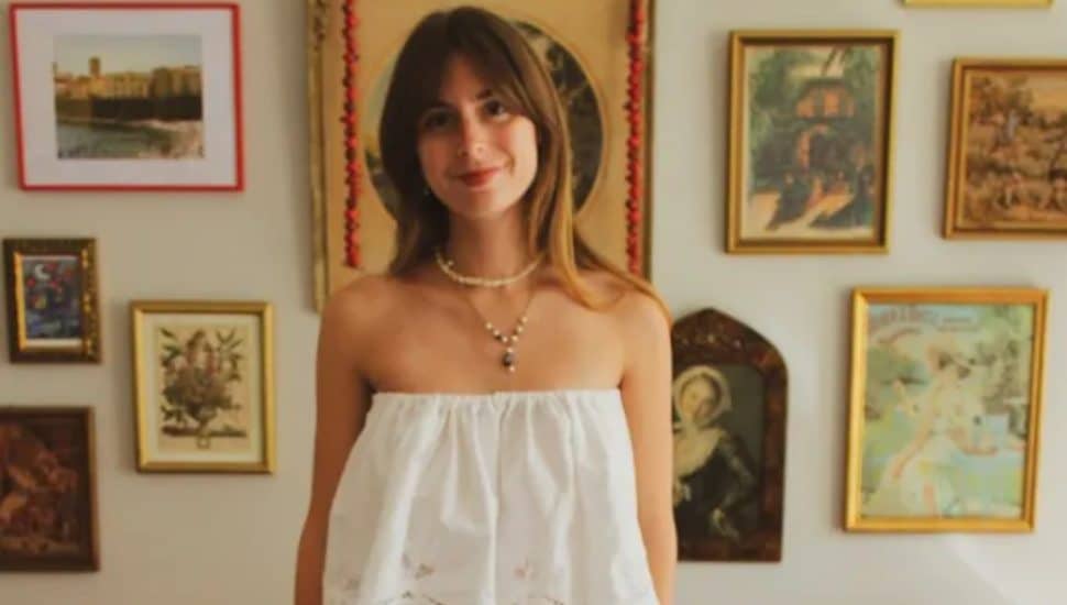 Fiona Duffy poses in her clothes with pictures on the wall behind her.