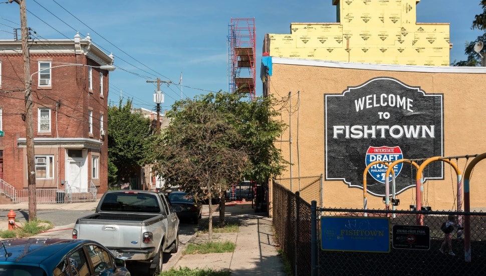 "Welcome to Fishtown" mural on side of building with a street.