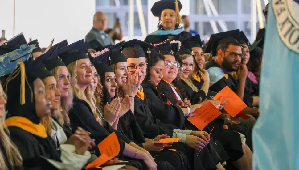 College graduates listen to a commencement speaker.