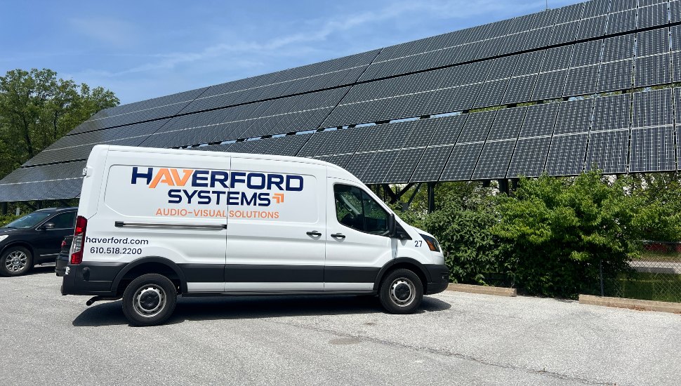 Van parked in front of solar panels.