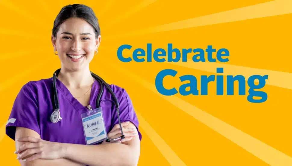 Female nurse in purple scrubs smiles for promotional campaign.