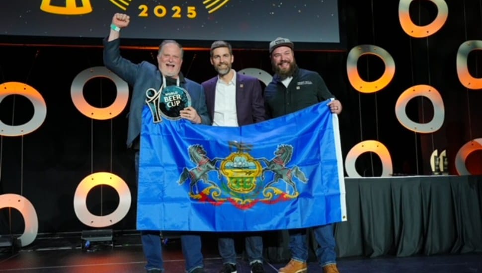 Three Iron Hill members on stage holding blue flag.