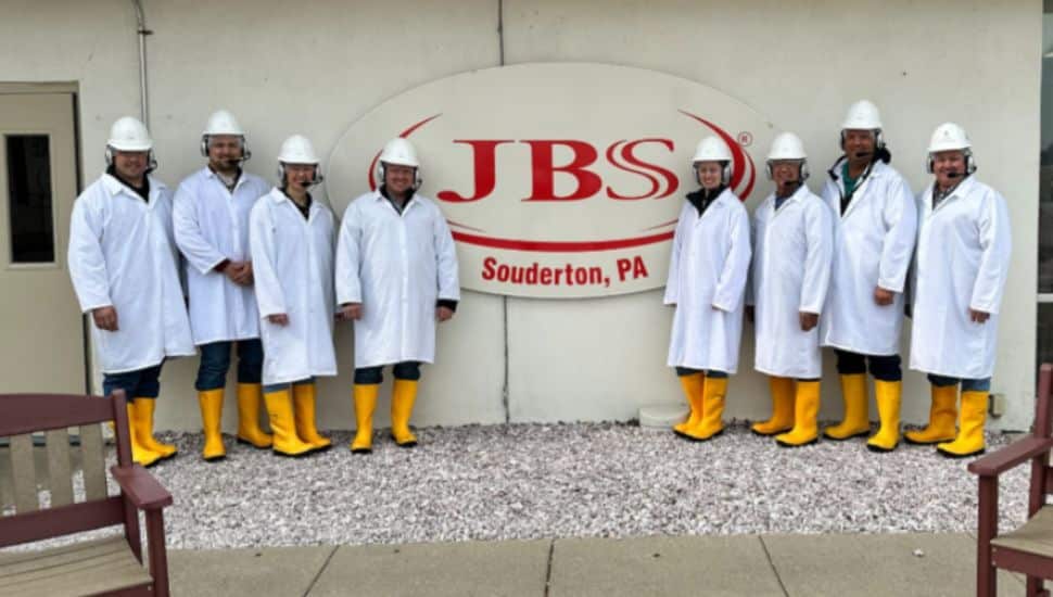 JBS Souderton workers in uniform stand in front of JBS sign.