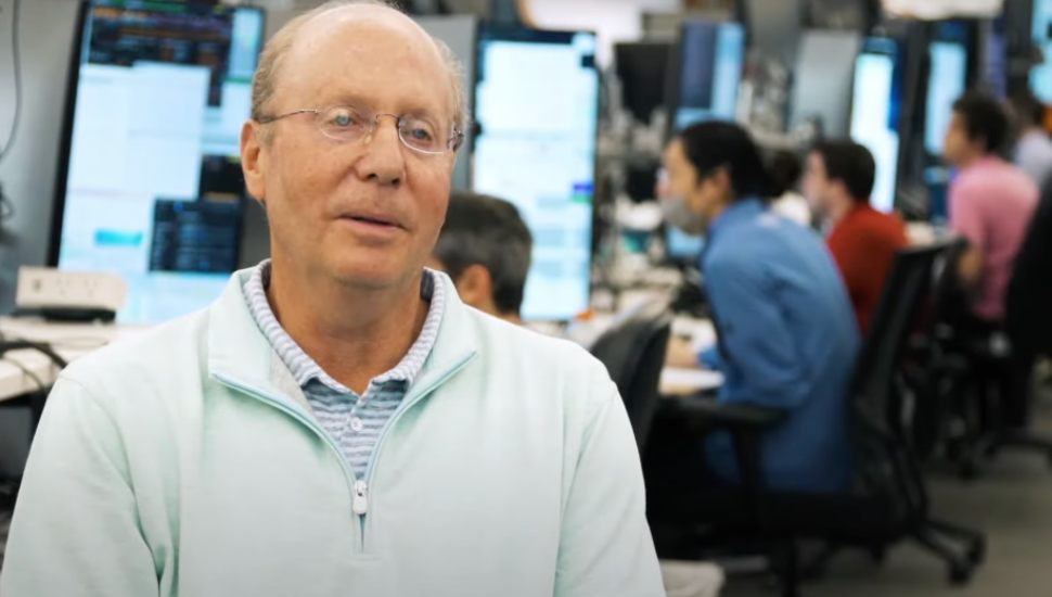 Jeff Yass sits at a trader's desk with busy people in background.
