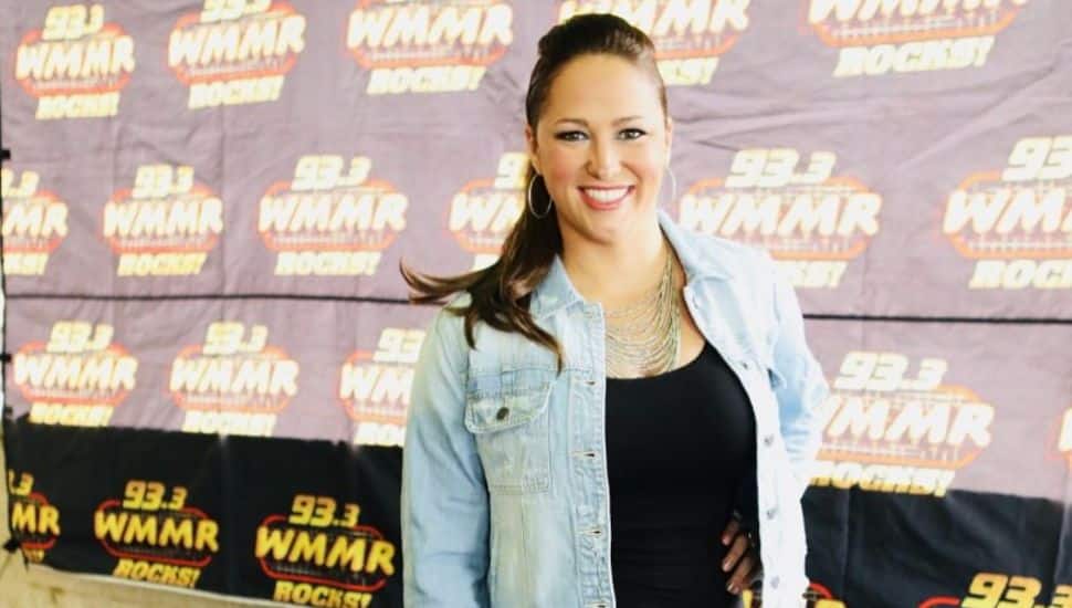 Kathy Romano wearing jean jacket with WMMR screen behind her.