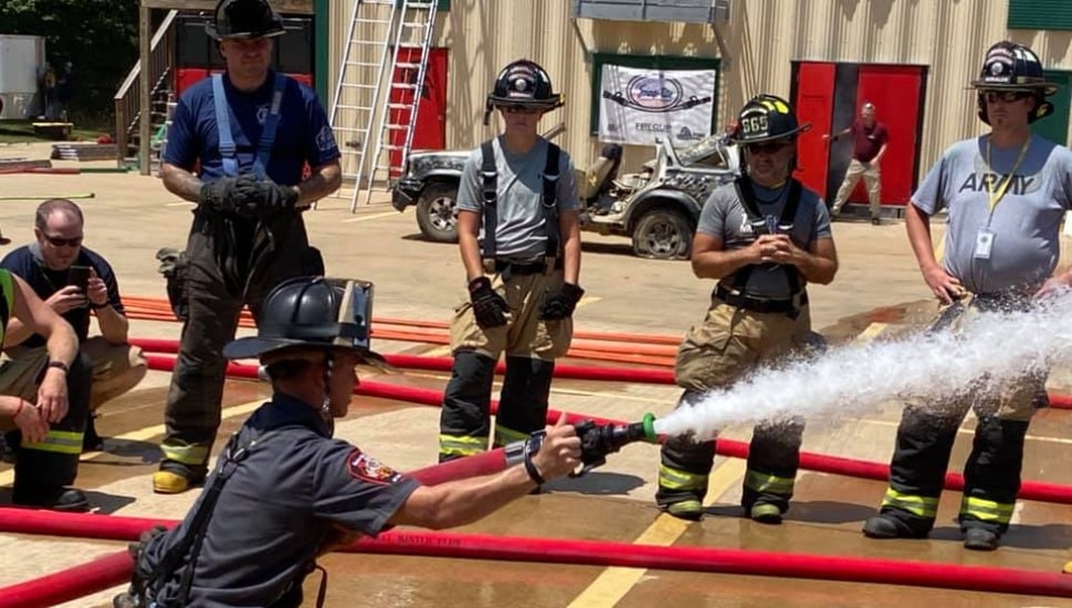 Firefighters gather and watch someone using Snap-tite Hose for a drill.
