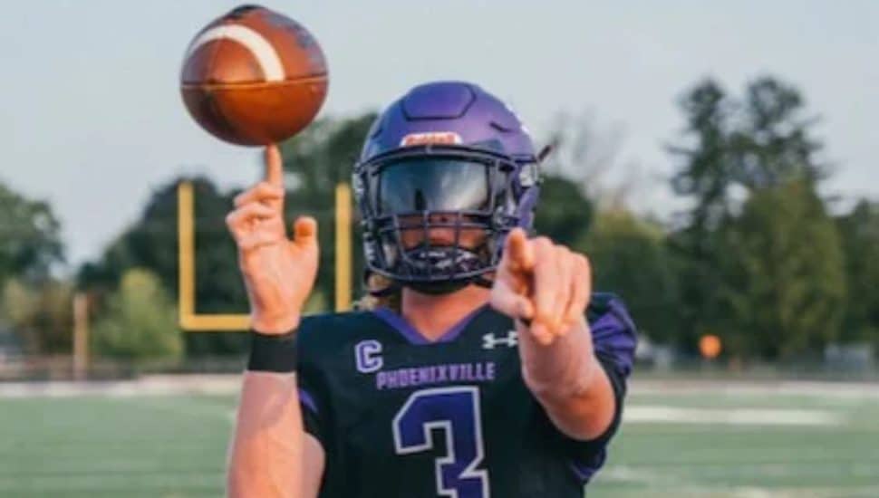 Talon Romance in football uniform holding football and pointing to camera.