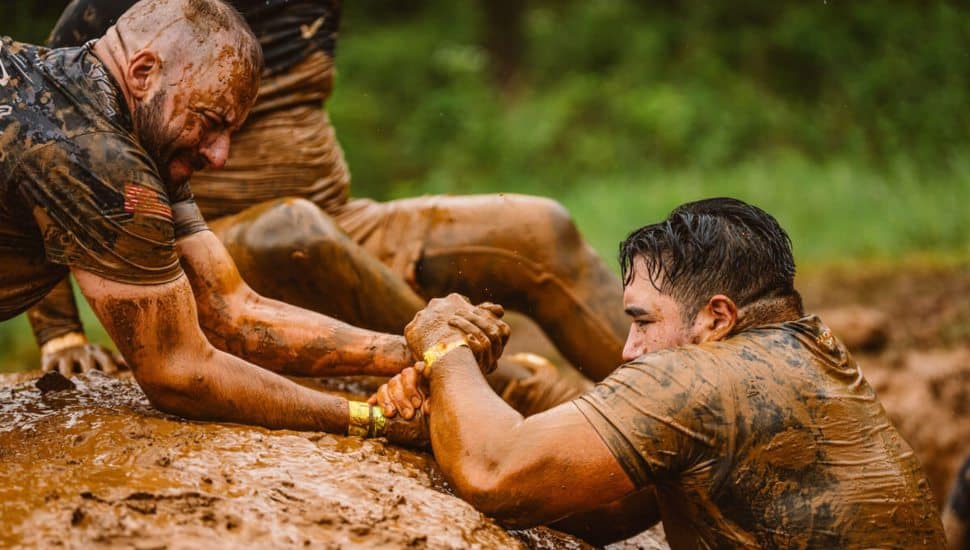 People struggling in the mud at Tough Mudder event.