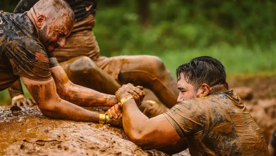 People struggling in the mud at Tough Mudder event.