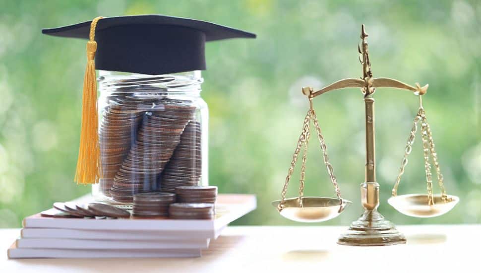 A jar filled with stacked coins wearing a graduation cap sits on top of books, symbolizing affordable education. Beside it is a brass balance scale, representing justice and legal education.
