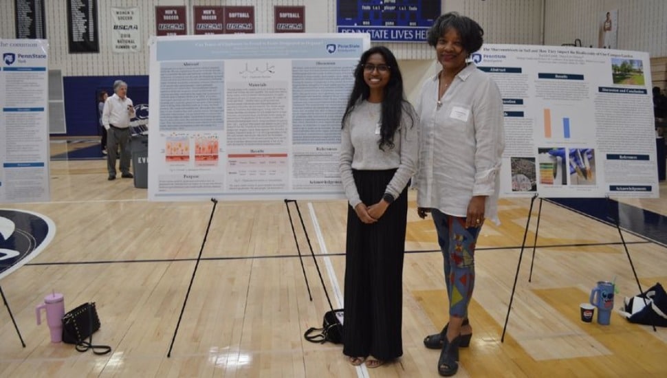 An unidentified student and professor stand near a presentation poster at the Penn State Eastern Regional Undergraduate Research Symposium hosted at Penn State Brandywine in Media Borough.