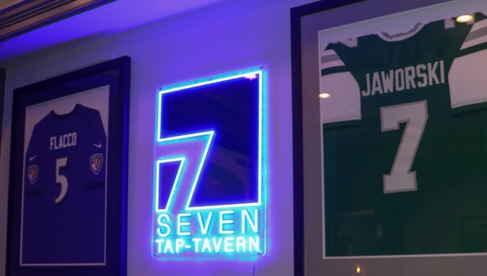 A glowing sign beside Ron Jaworski's Eagles jersey at 7-Tap Tavern.