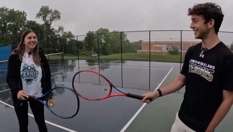 Ava and Gabriel Shapiro holding tennis rackets at a tennis court outside.