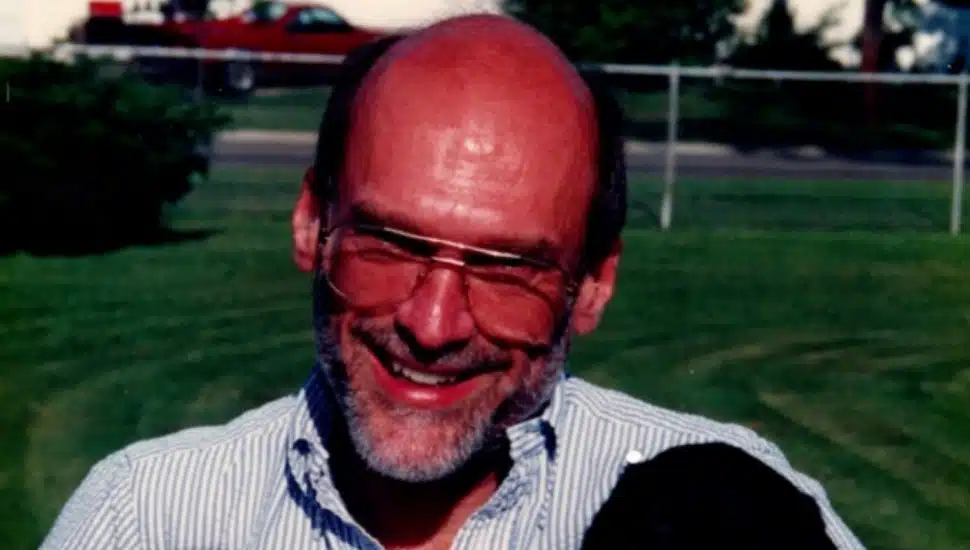 Headshot of middle-aged man with bald head, gray beard, and glasses.
