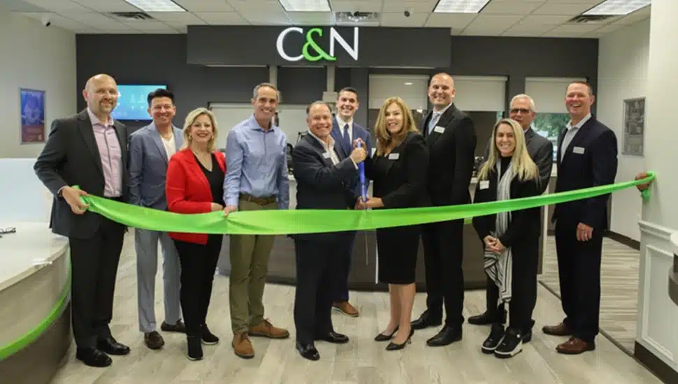 Bank executives cut ribbon on new office.