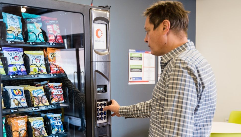 Man using Cantaloupe tech payment at vending machine.