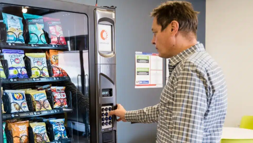 Man using Cantaloupe tech payment at vending machine.