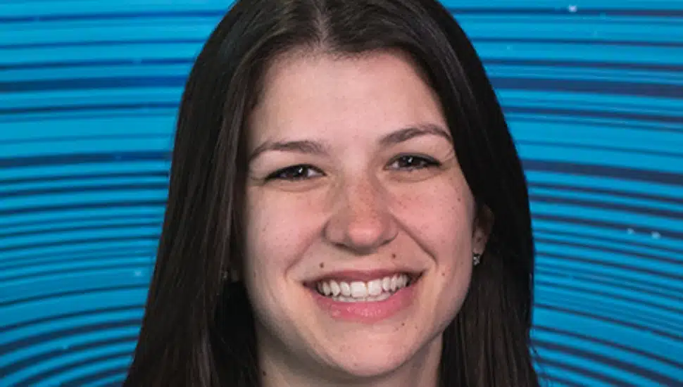 Emily Gatto: She has long dark hair and smiles warmly in front of a vibrant blue background with curved line patterns.