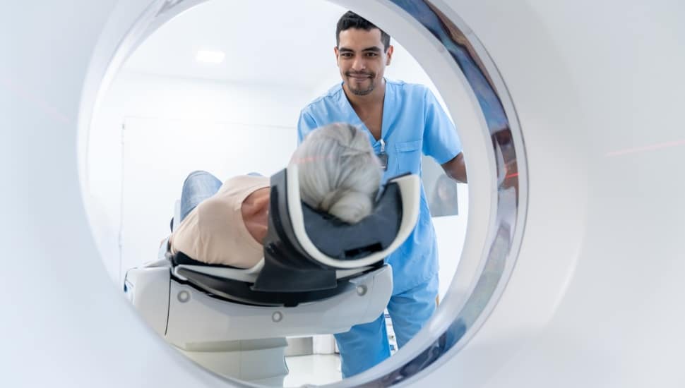 Technician puts older man in MRI machine.