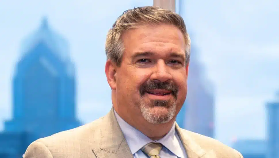 Scott Sauer headshot with buildings in background.