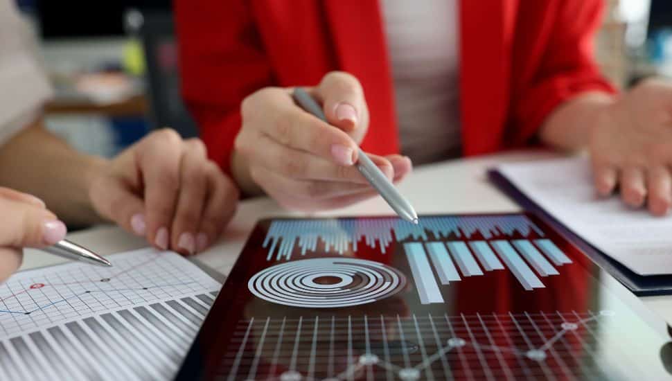 Business women studying charts and diagrams on digital tablet closeup