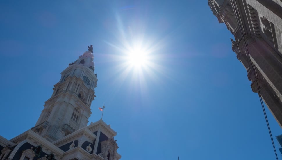 Sun beating down on ground with building tops in view.