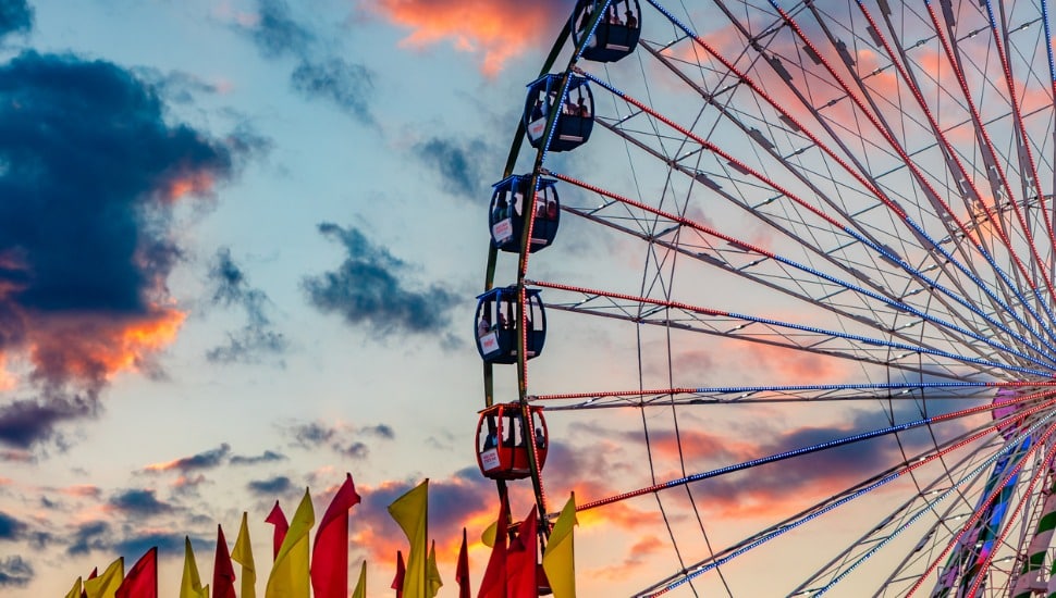 A ferris wheel in front of a cloudy sunset.