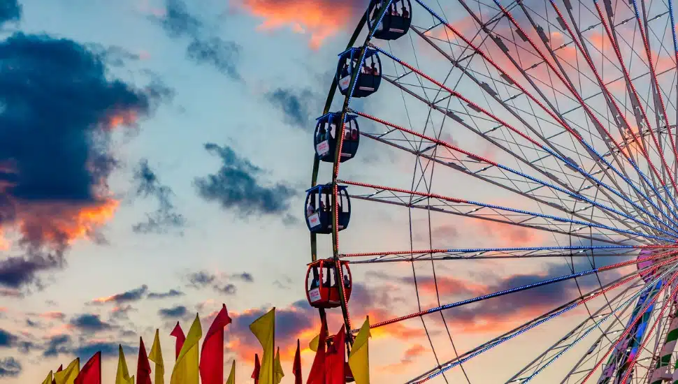A ferris wheel in front of a cloudy sunset.