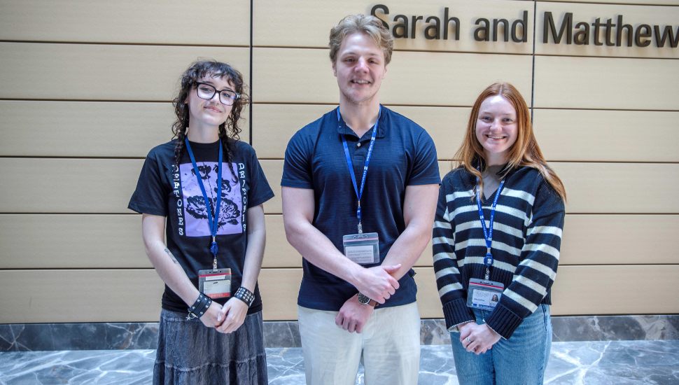 Three Delaware County Community College students—Lillian Yost, Kyle Hocevar, and Eden VanDyke—pose together wearing name badges at the Wistar Institute, where they participated in the 2025 Biomedical Technician Training Program.