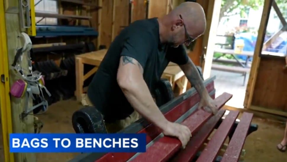 Man building a red bench built from plastic bags.