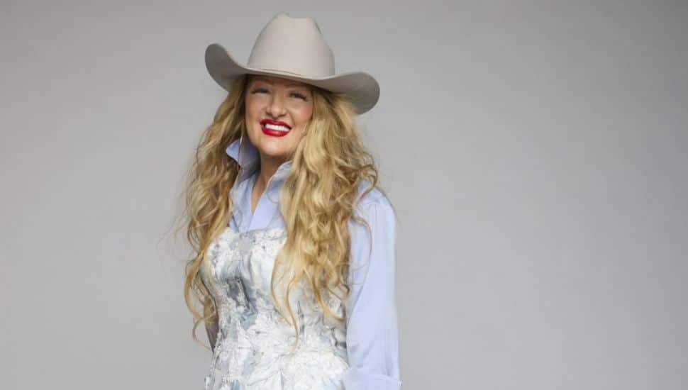 David's Bridal CEO Kelly Cook is wearing a dress and a cowboy hat.