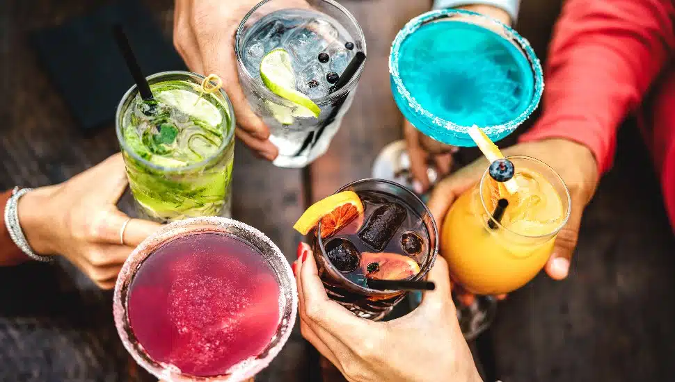 Several people toasting with colorful mocktails.