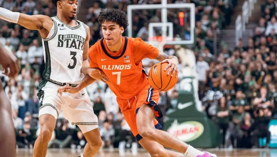 Will Riley in orange jersey on the court with basketball in hand.
