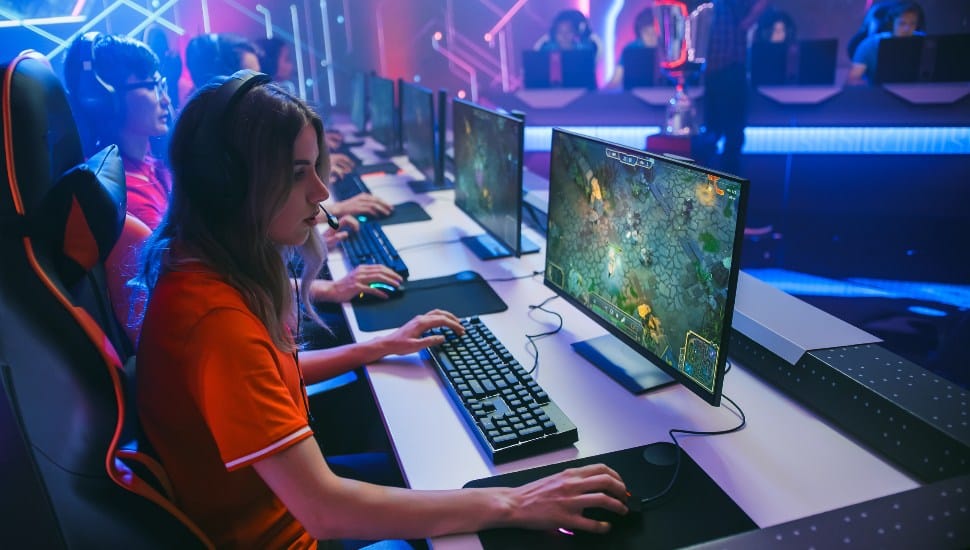 Kids playing games on computer in neon esports lab.
