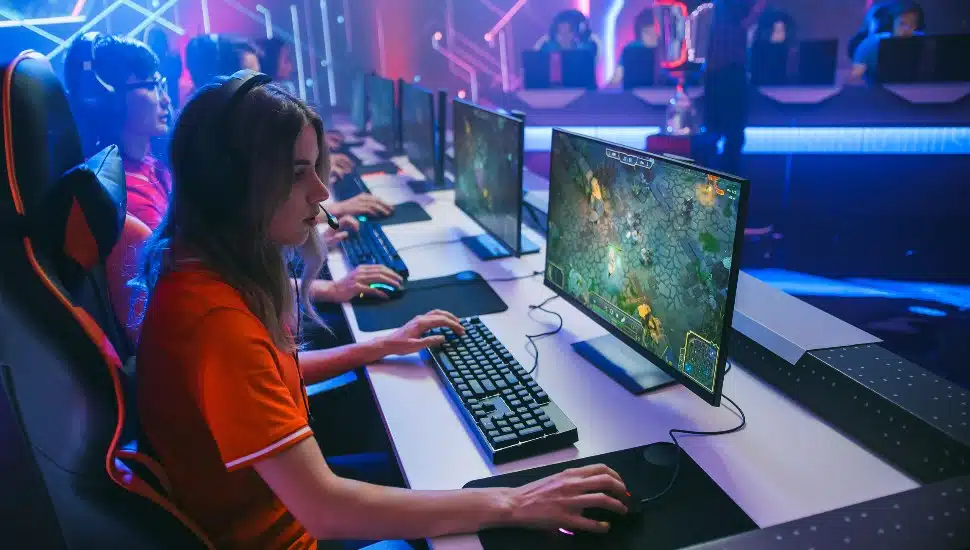 Kids playing games on computer in neon esports lab.