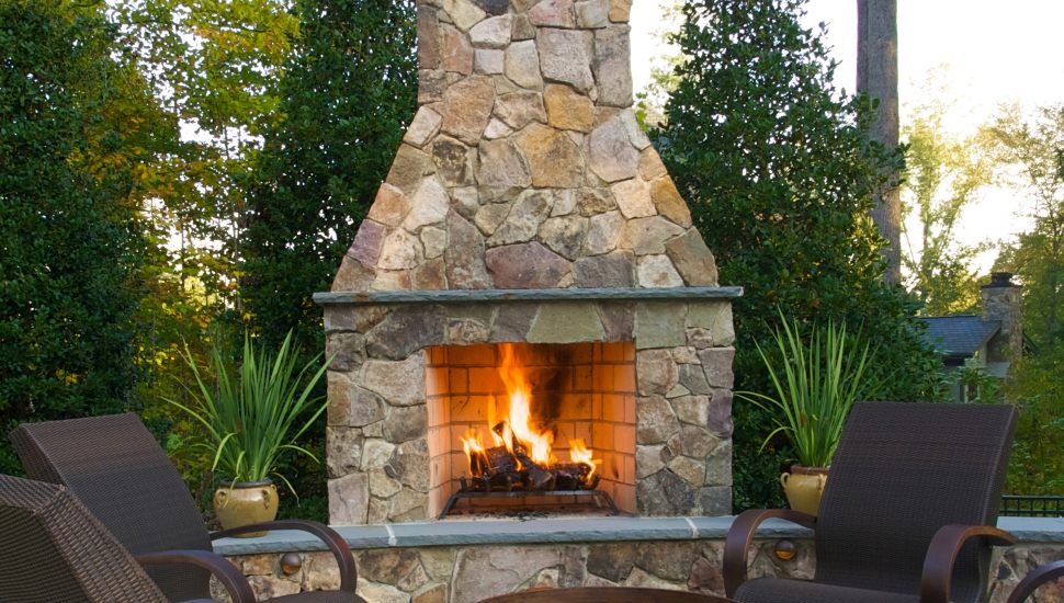 Outdoor fireplace with chairs and fire going.