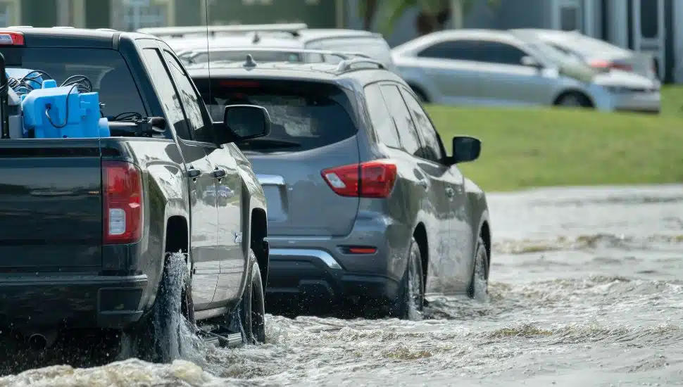 Two cars driving in rain-flooded roads.