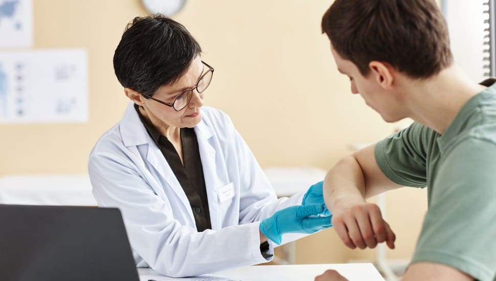 Female derm doc examining male patient's arm.